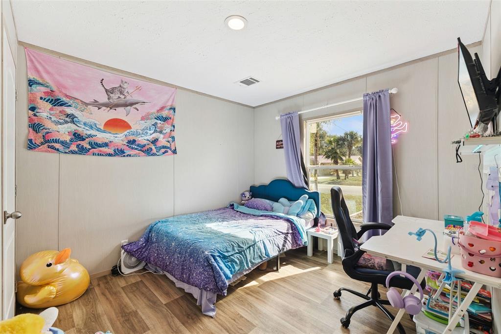 231 Tropic Avenue Satsuma, FL 32189 - Photo 11 of 28 a bedroom with a bed and wooden floor