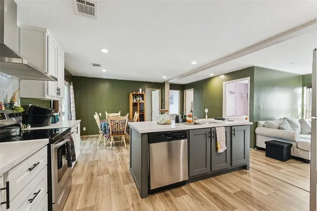 a view of a kitchen with kitchen island a sink a counter space stainless steel appliances and cabinets