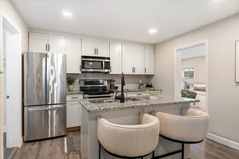 a kitchen with stainless steel appliances granite countertop a sink a stove a refrigerator and cabinets