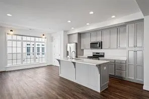 a kitchen with stainless steel appliances granite countertop a stove a sink a refrigerator white cabinets and wooden floor