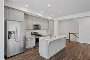 a kitchen with stainless steel appliances a refrigerator a stove a sink cabinets and wooden floor