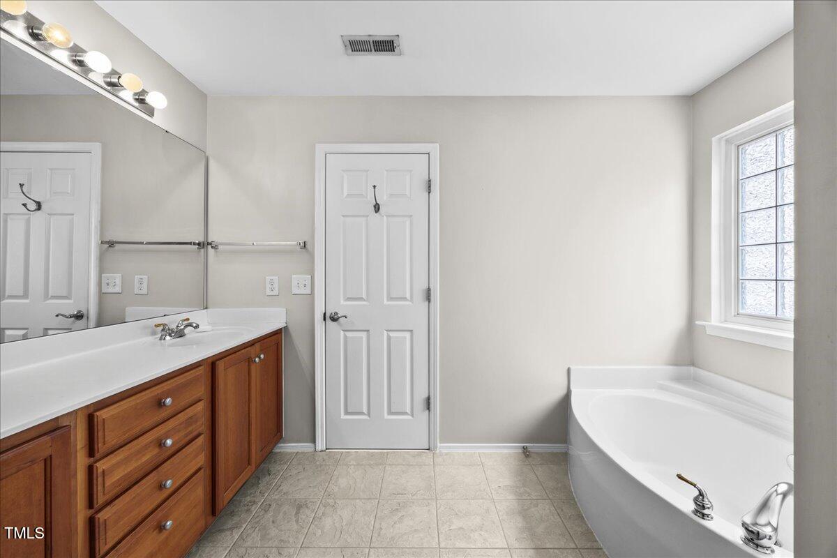 8404 Split Stone Lane Raleigh, NC 27613 - Photo 29 of 45 a bathroom with a tub a sink and mirror