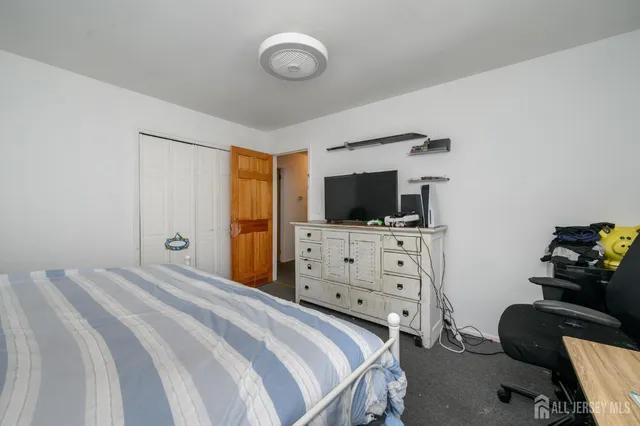 a bedroom with a flat screen tv on the dresser and a flat screen tv