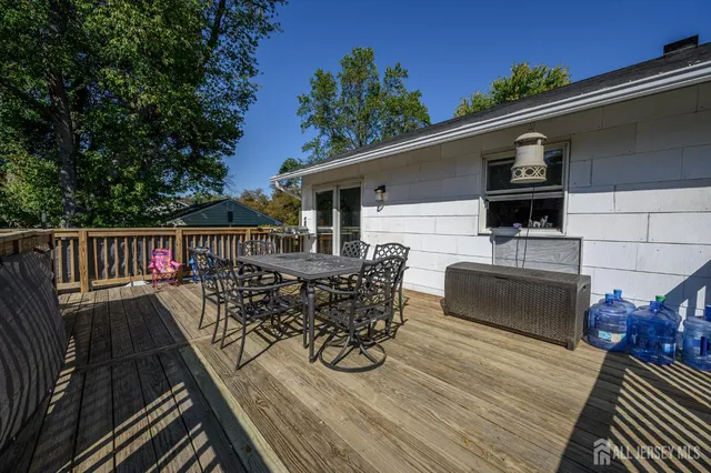 a view of a roof deck with table and chairs a barbeque with wooden floor and fence