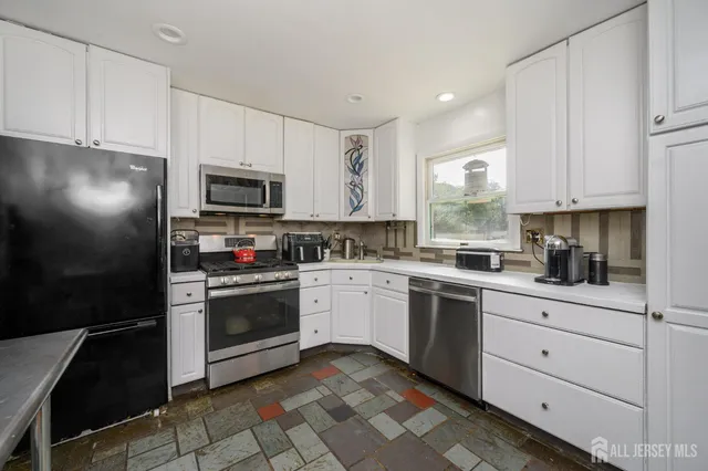 a kitchen with granite countertop white cabinets and stainless steel appliances
