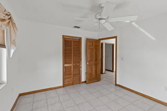 an empty room with chandelier fan and closet
