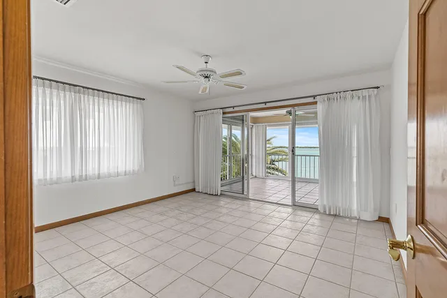 a view of an empty room with window and chandelier fan