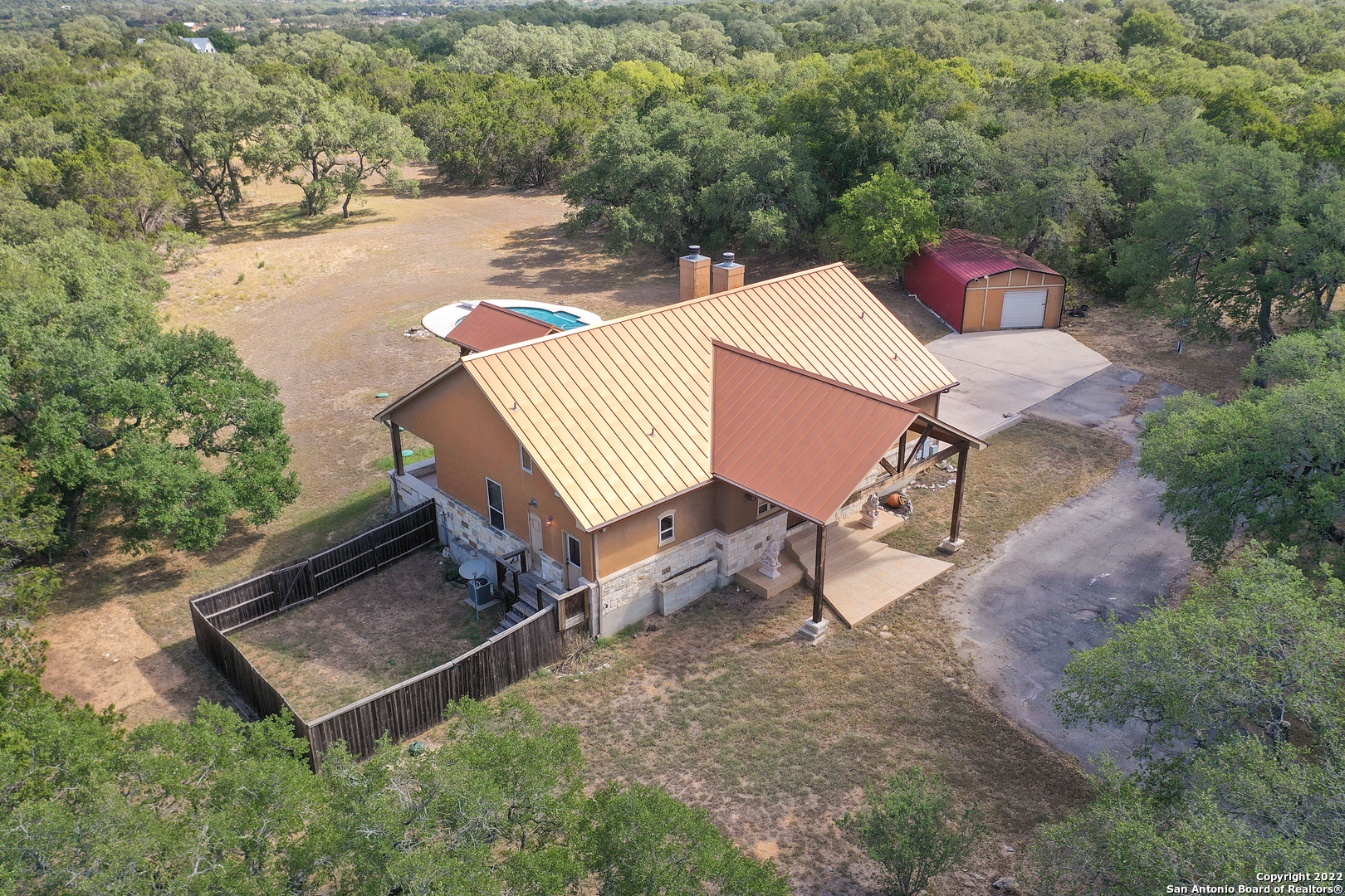 an aerial view of a house with backyard and trees