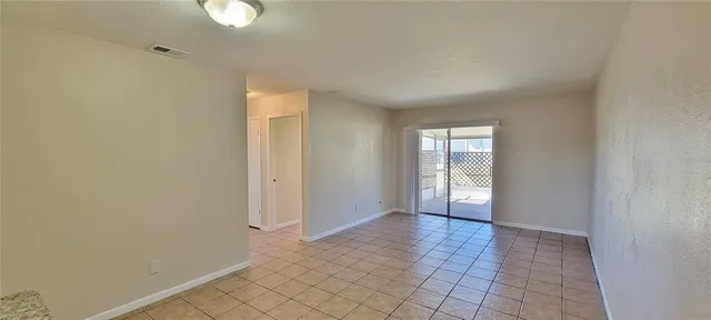 a view of an empty room with window and chandelier fan