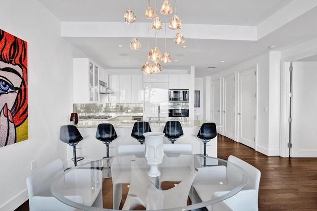 a kitchen with stainless steel appliances kitchen island granite countertop a refrigerator a stove a kitchen island with chairs and wooden floor