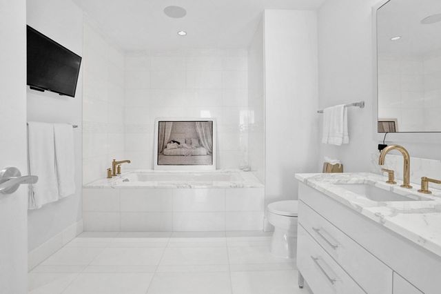 a bathroom with a sink a flat screen tv and a toilet