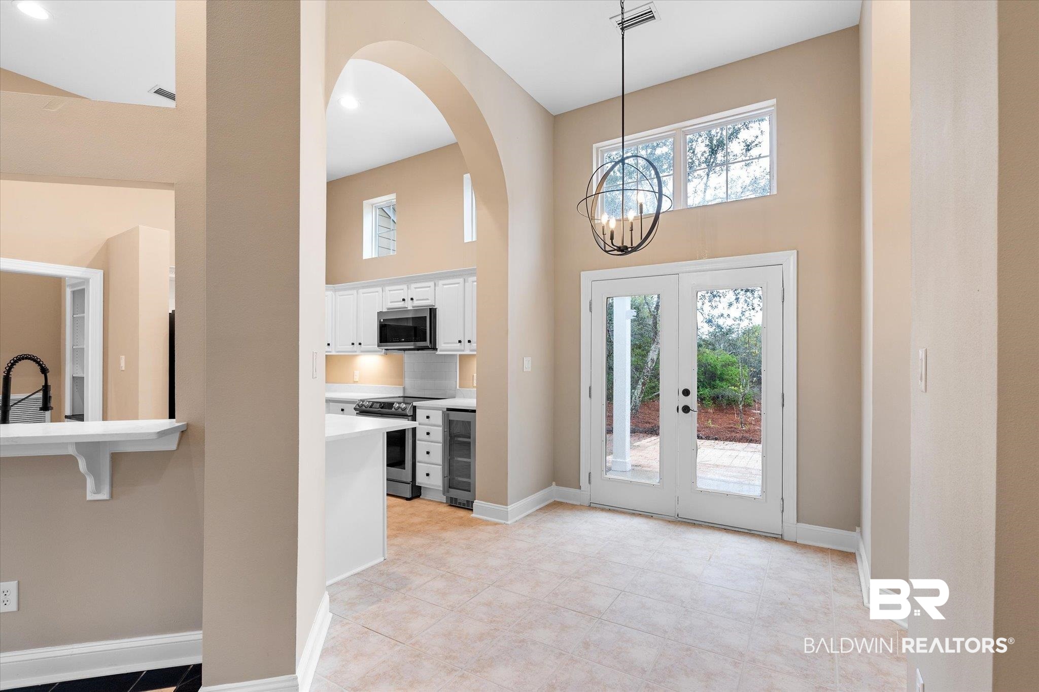 9259 Genipa Way Gulf Shores, AL 36542 - Photo 10 of 72 Foyer with french doors, light tile patterned flooring, an inviting chandelier, a high ceiling, and beverage cooler