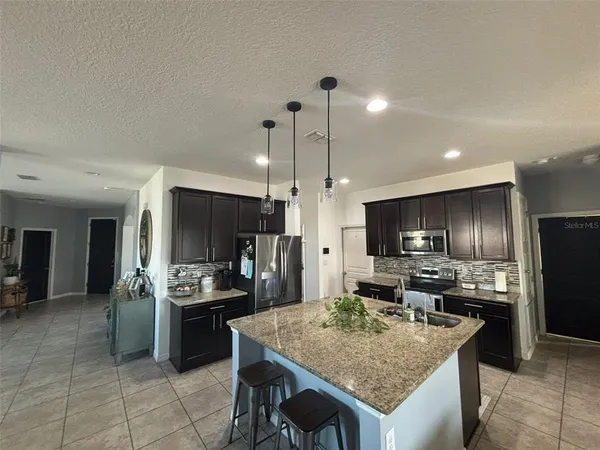 a kitchen with stainless steel appliances granite countertop a sink refrigerator and cabinets