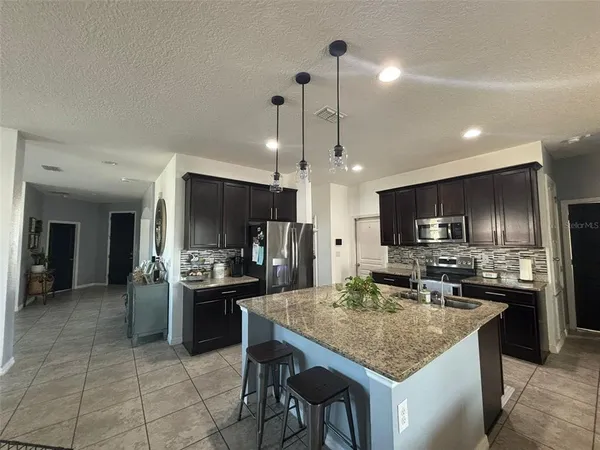 a kitchen with kitchen island granite countertop a sink stove and refrigerator