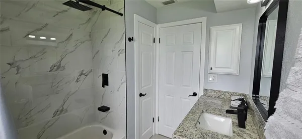 a bathroom with a granite countertop shower and a sink