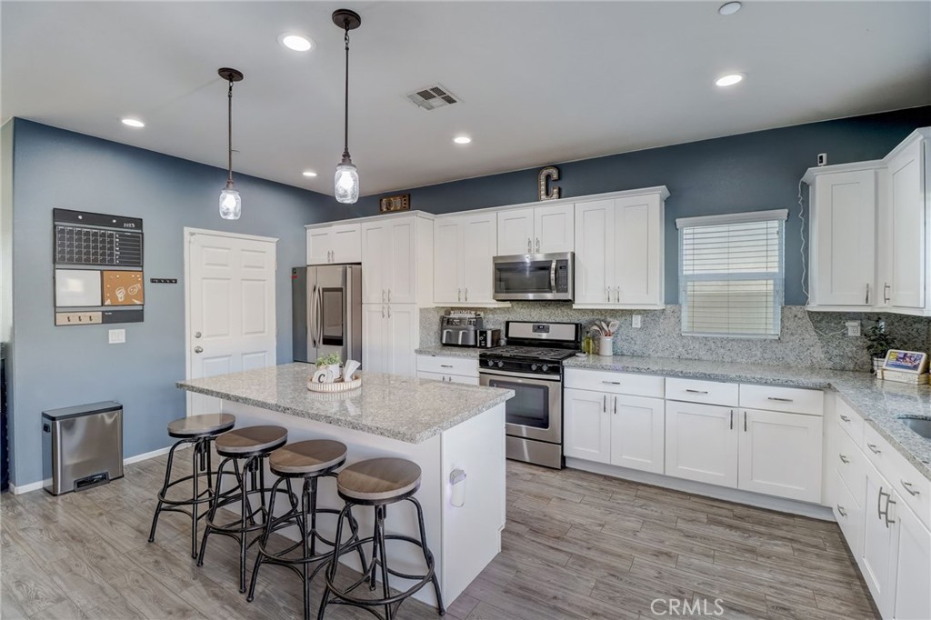1667 Constant Trail San Jacinto, CA 92582 - Photo 12 of 44 a kitchen with stainless steel appliances granite countertop a sink a stove a refrigerator cabinets and chairs