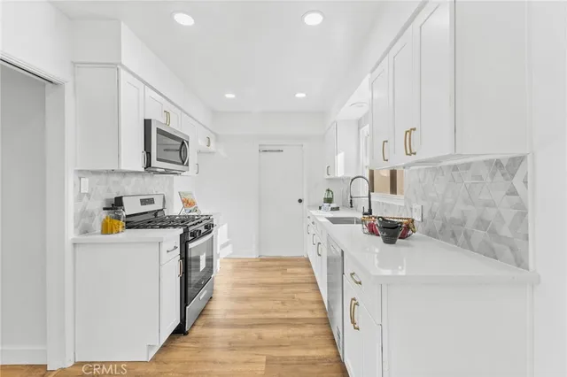 a kitchen with stainless steel appliances a stove a microwave and a hard wood floor
