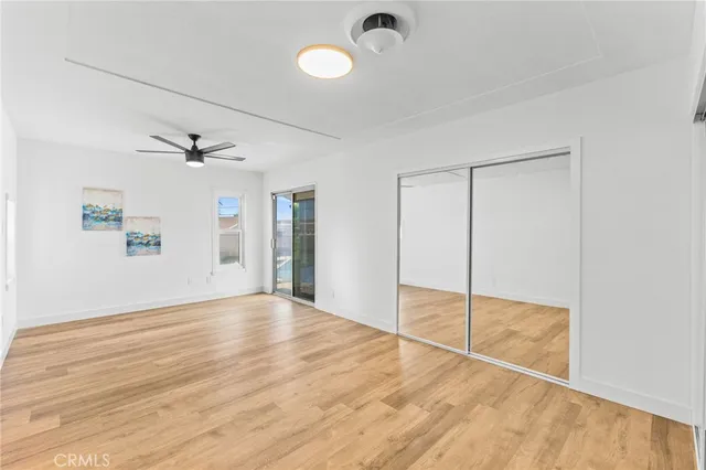 a view of a room with wooden floor ceiling fan and window