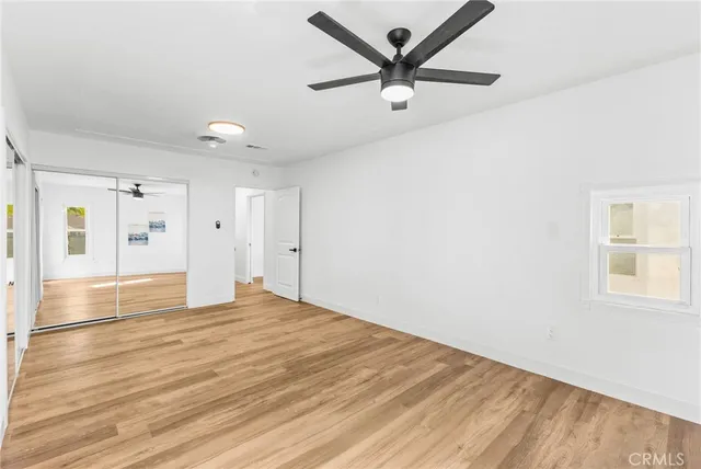 an empty room with wooden floor and ceiling fan