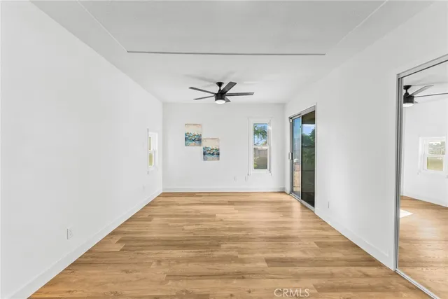 a view of empty room with wooden floor and fan