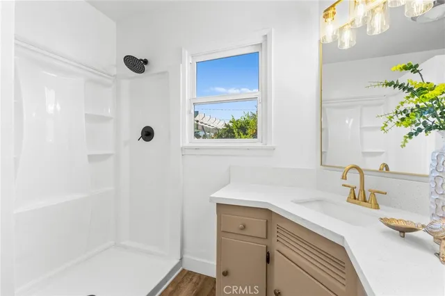 a view of a hallway with wooden floor and a bathroom