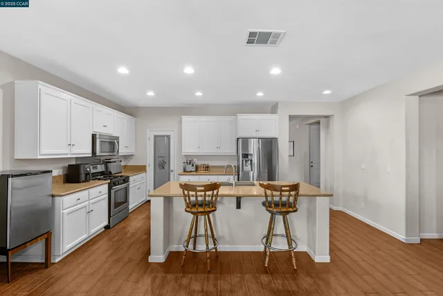 a kitchen with stainless steel appliances kitchen island granite countertop a refrigerator and a stove top oven