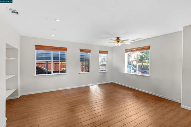 a view of an empty room with a window and wooden floor