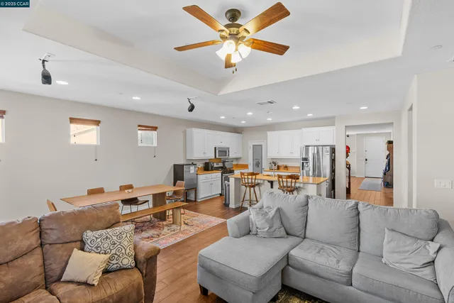 a living room with furniture kitchen view and a chandelier