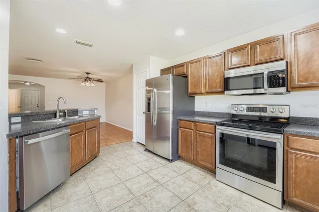 a kitchen with stainless steel appliances granite countertop a stove top oven microwave and refrigerator