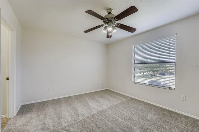 an empty room with a window and a fan
