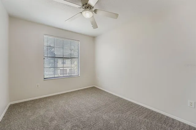 an empty room with a window and a fan