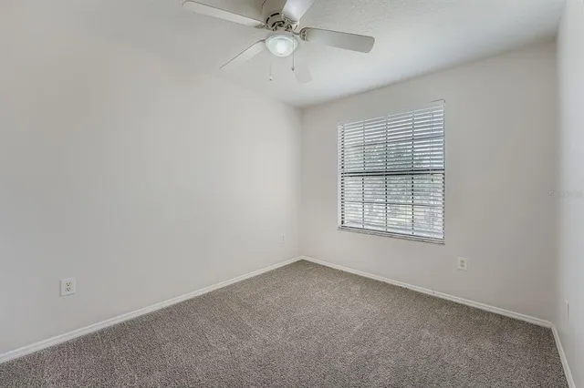 an empty room with a window and a fan