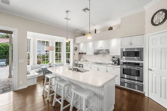 a large white kitchen with a large window and stainless steel appliances