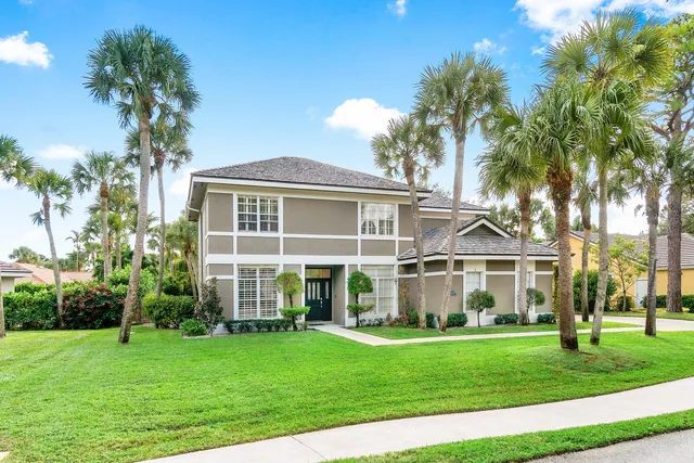 a view of a house with a yard and palm trees