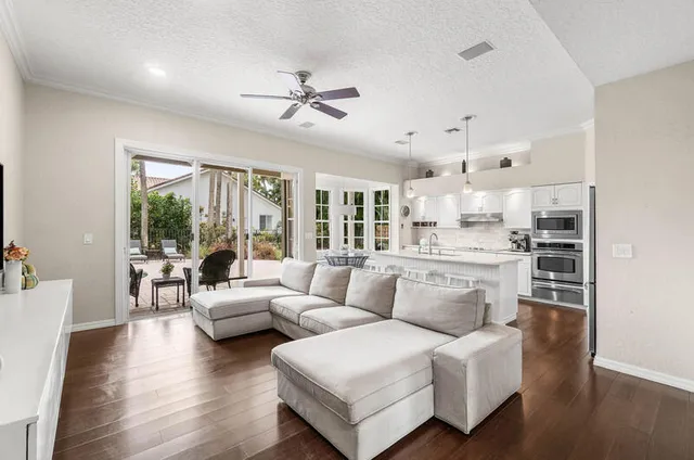 a living room with furniture kitchen view and a chandelier