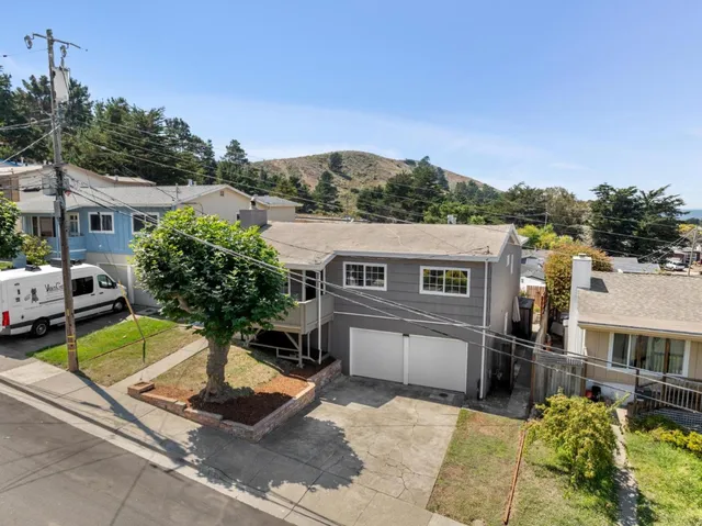 a front view of residential houses with yard and mountain view in back