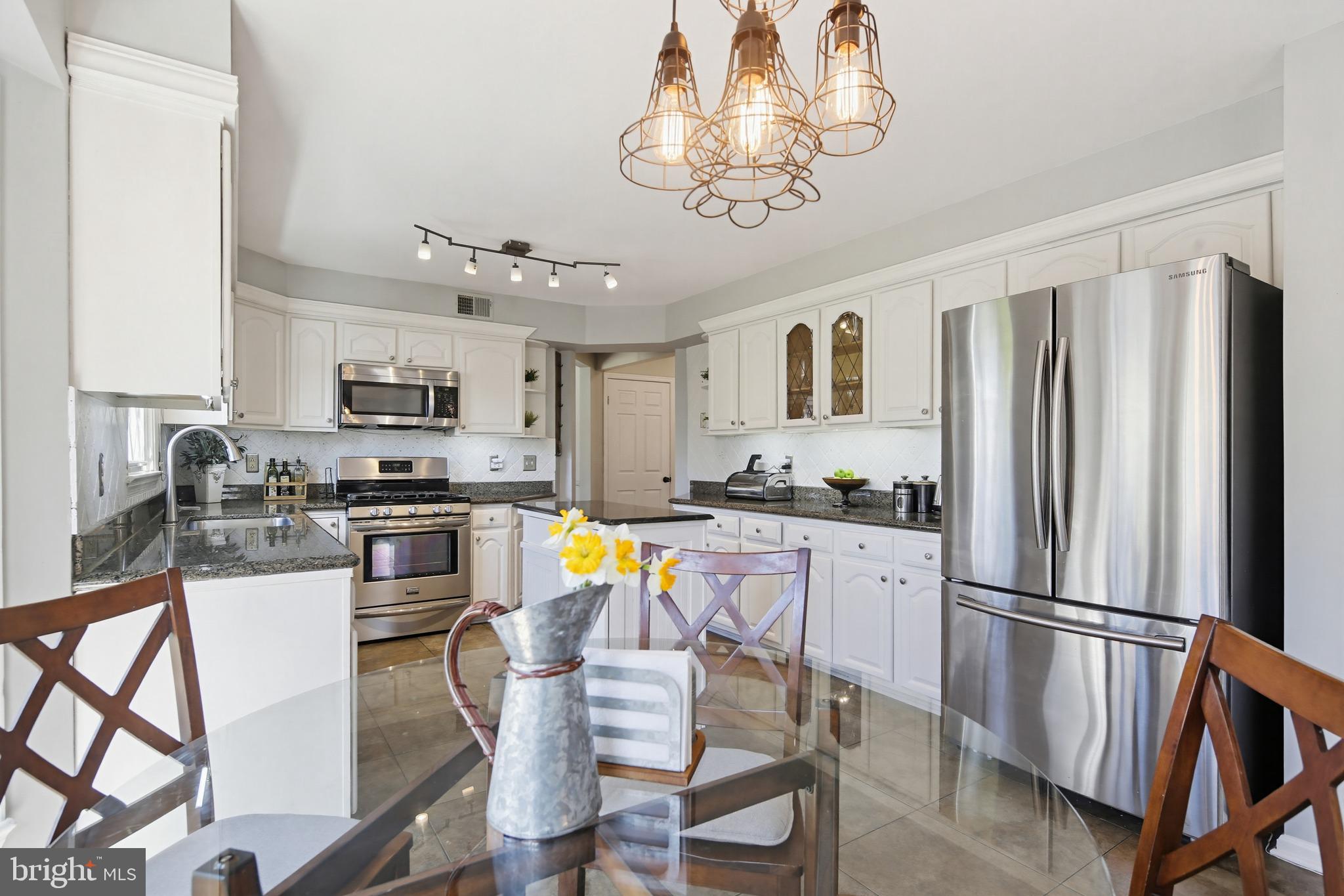 18906 Lindenhouse Road Gaithersburg, MD 20879 - Photo 18 of 48 a kitchen with stainless steel appliances granite countertop a refrigerator a stove top oven a sink dishwasher and a dining table with wooden floor
