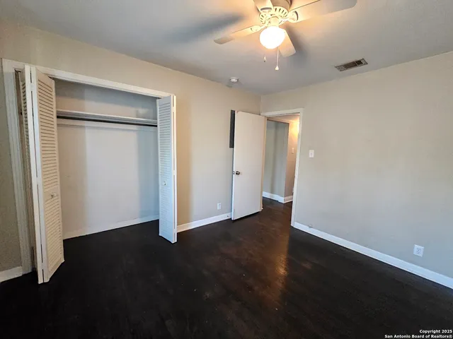 an empty room with wooden floor and a ceiling fan