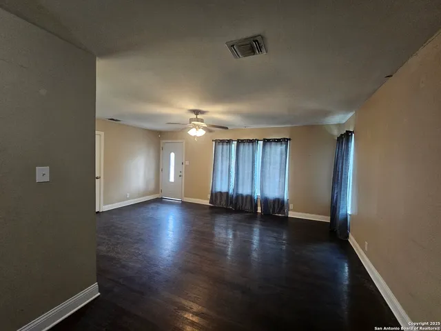 an empty room with wooden floor and windows