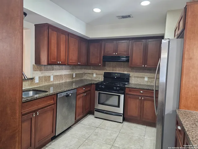 a kitchen with stainless steel appliances granite countertop a refrigerator and a sink