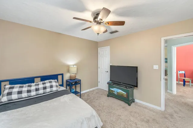 a bedroom with a bed and a flat tv screen on dresser