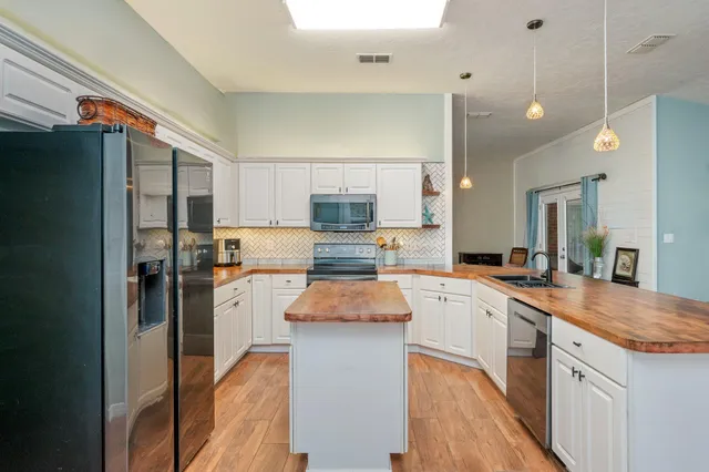 a kitchen with stainless steel appliances granite countertop sink stove refrigerator and cabinets
