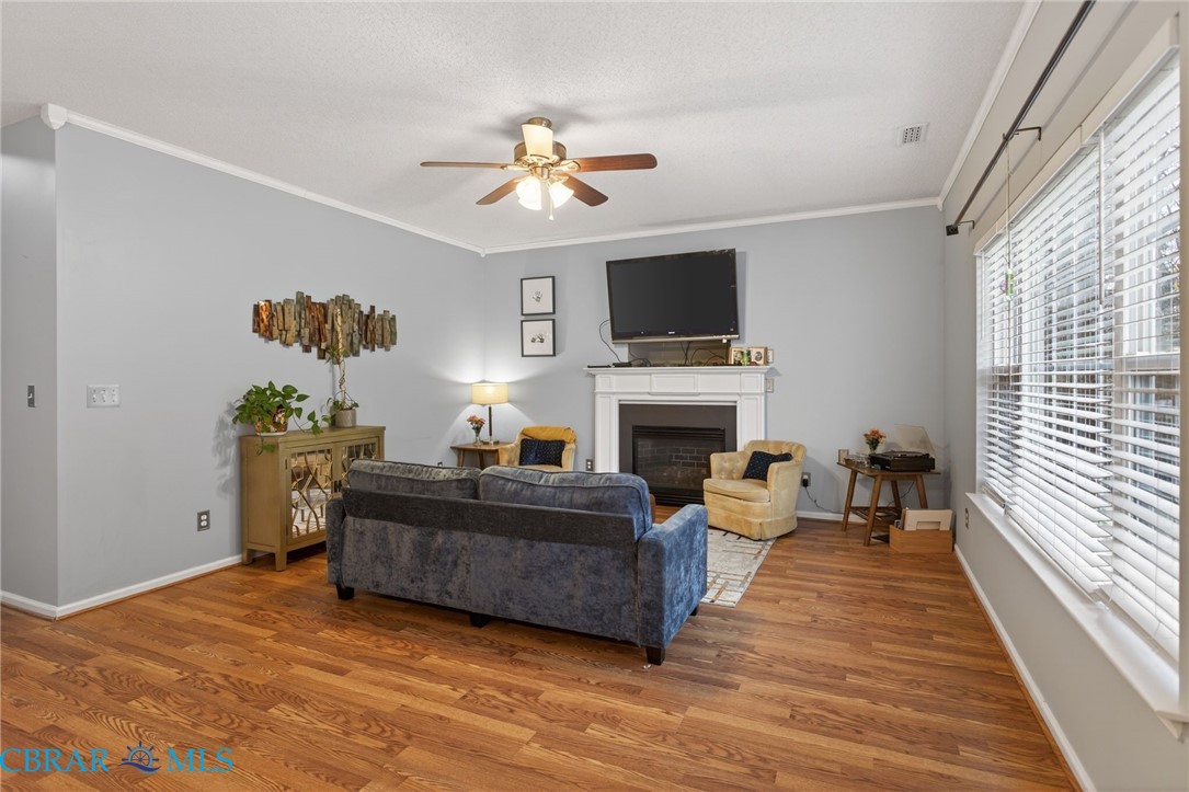 116 Old Field Road Williamsburg, VA 23188 - Photo 5 of 27 Living area featuring a fireplace, ceiling fan, crown molding, wood finished floors, and a textured ceiling