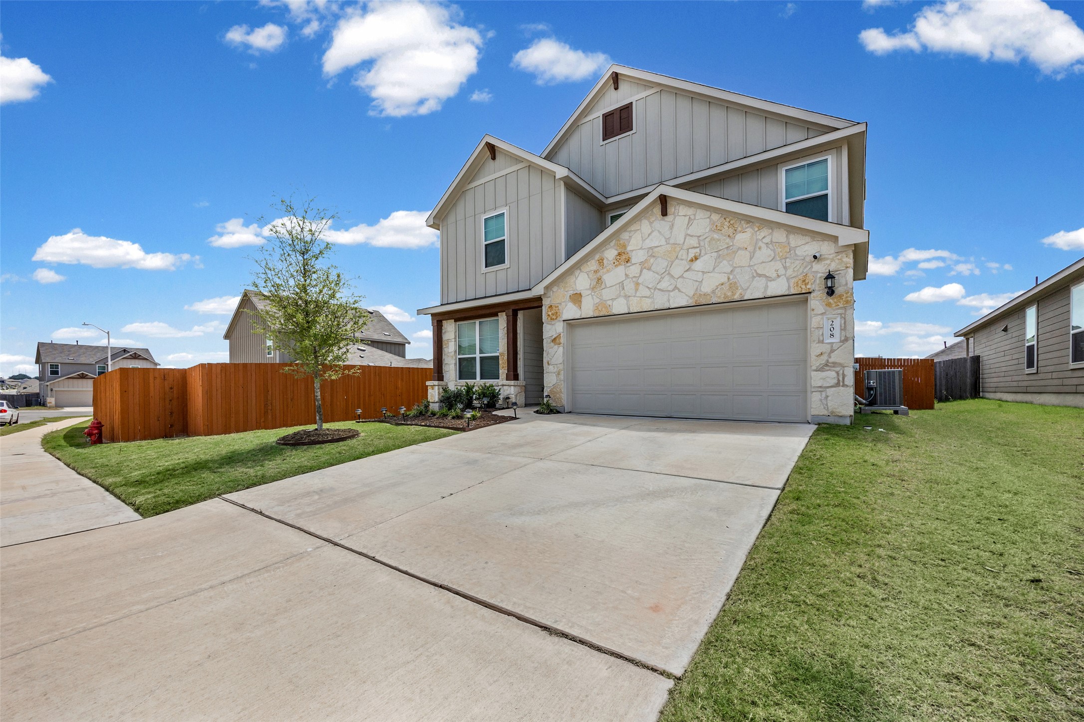 208 Orange Road Buda, TX 78610 - Photo 8 of 31 A striking modern residence boasts a harmonious blend of stone and siding, complemented by a neatly manicured lawn.