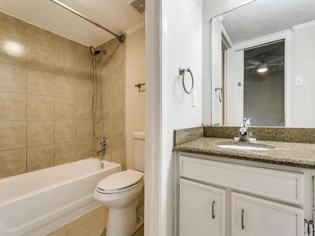 a bathroom with a granite countertop sink toilet mirror and bathtub