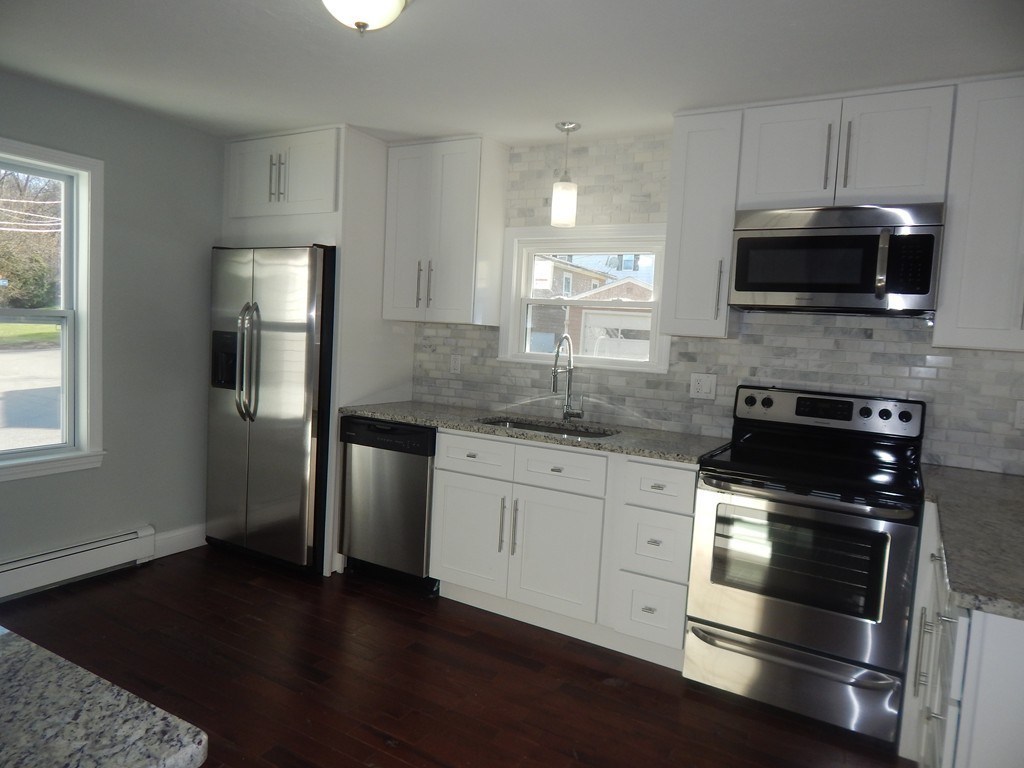 57 Conant Road Framingham, MA 01702 - Photo 5 of 25 a kitchen with stainless steel appliances kitchen island granite countertop a stove a sink and a microwave