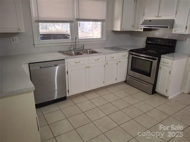 a kitchen with white cabinets appliances and a window