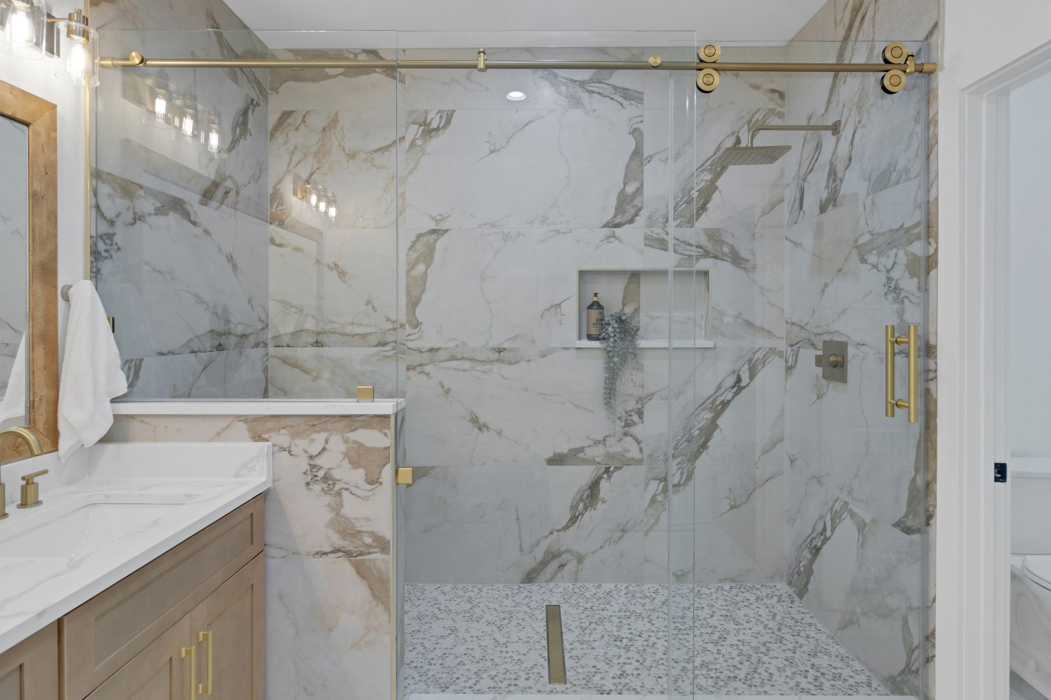 4202 Plaag Street Houston, TX 77016 - Photo 27 of 38 Stunning walk-in shower with floor-to-ceiling porcelain tile, frameless glass enclosure, built-in seating area, and a convenient soap alcove for added functionality.