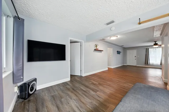 a view of empty room with wooden floor and fan