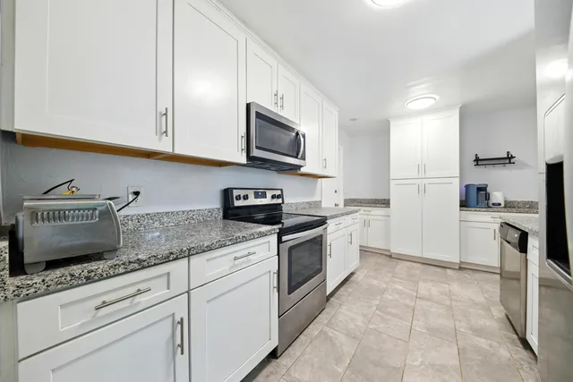 a kitchen with granite countertop white cabinets stainless steel appliances and a sink